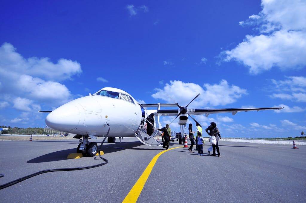 A group of people board a propeller airplane on a sunny day in Fuvahmulah, Maldives.