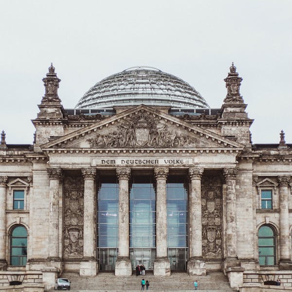 Front view of the historic Reichstag Building in Berlin, Germany, featuring prominent German flags.