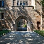 Gothic-style stone archway entrance at Yale University campus, surrounded by greenery.