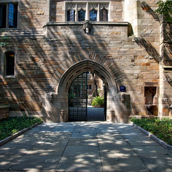 Gothic-style stone archway entrance at Yale University campus, surrounded by greenery.