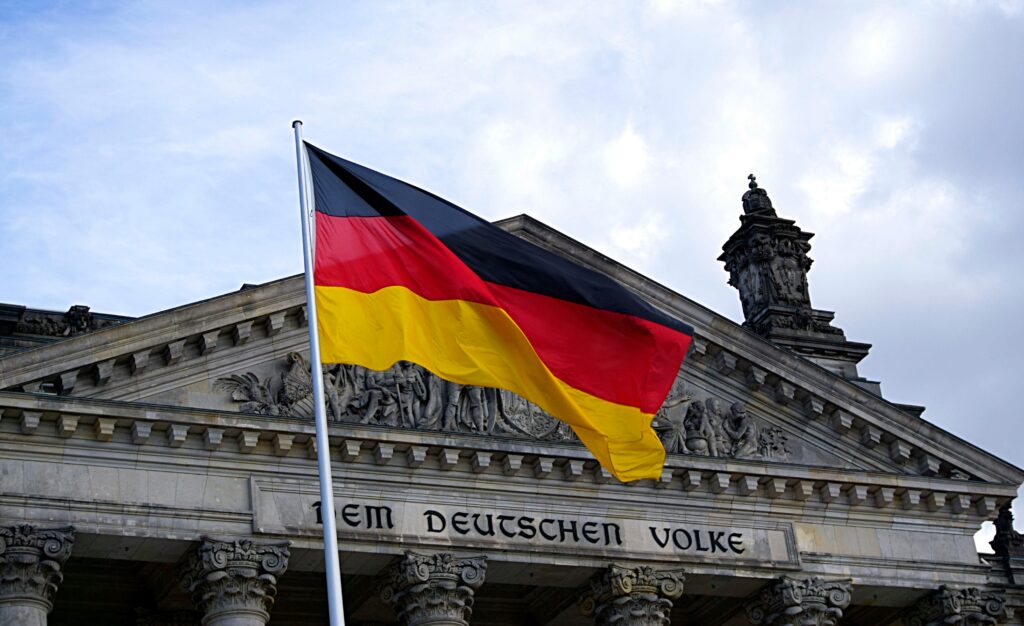 pexels-photo-109629-109629 German national flag waving in front of the Reichstag building in Berlin, a symbol of democracy.
